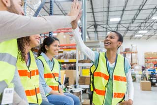 Warehouse employee receives congratulations during team meeting